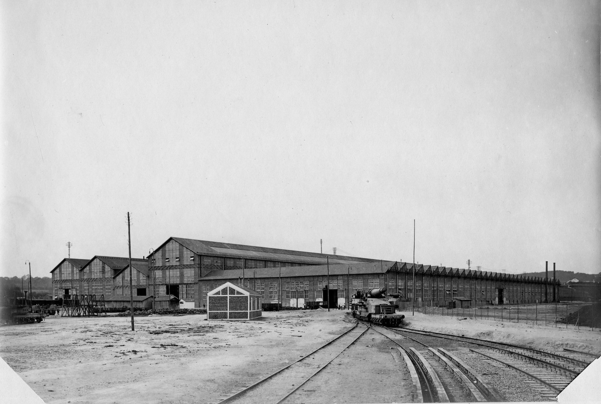 Vue extérieure d'une partie des ateliers d'artillerie du Creusot : atelier des gros obus. Canon en cours de sortie. 1916. Collection AFB.
